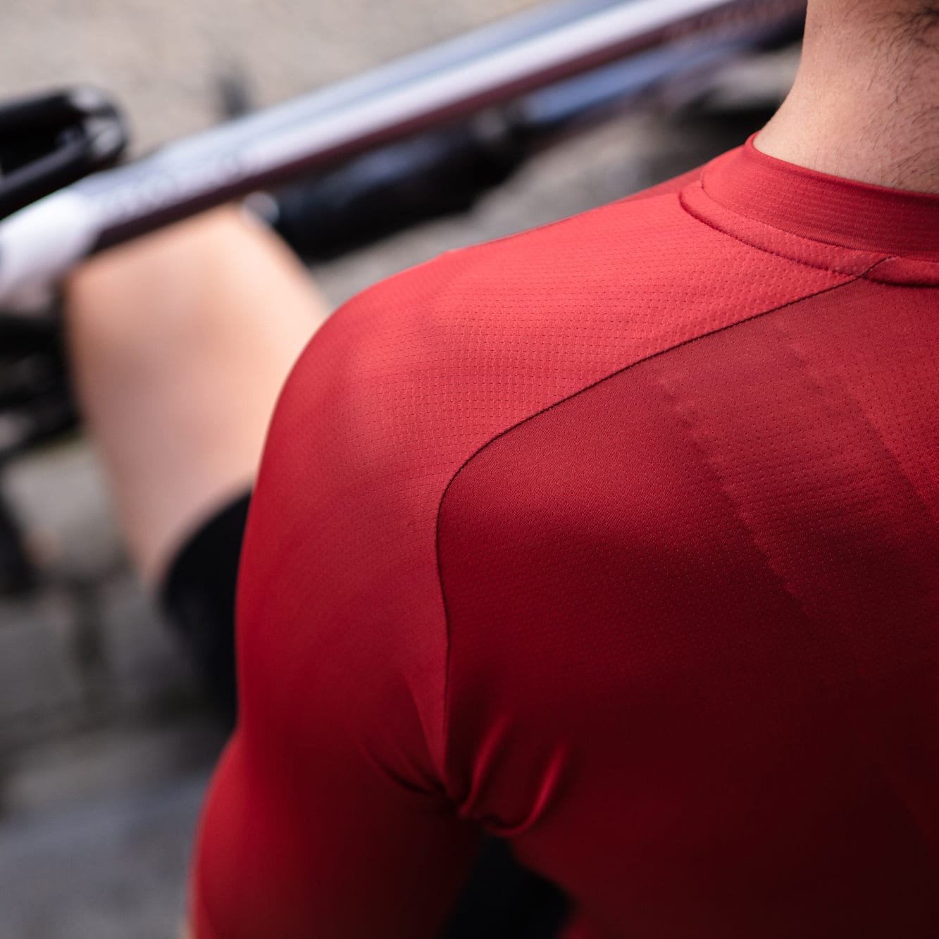 Close-up of a cyclist wearing the red Bioracer Metallix jersey, showing detailed shoulder seam and textured breathable fabric.