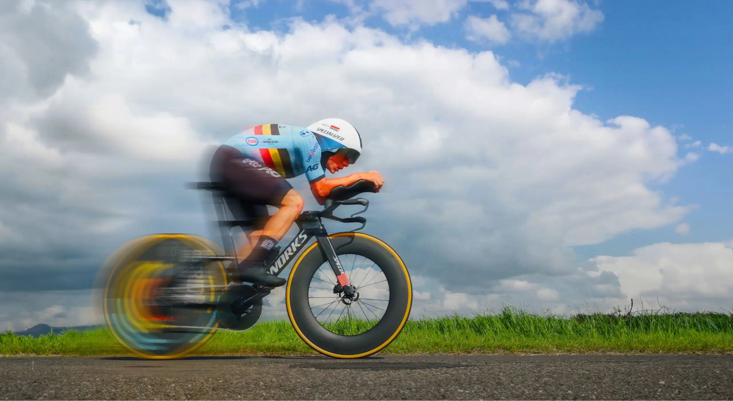 Belgian national team cyclist performing outdoor field testing in Bioracer aerosuit, showcasing race-proven speedwear on open road under dynamic sky.