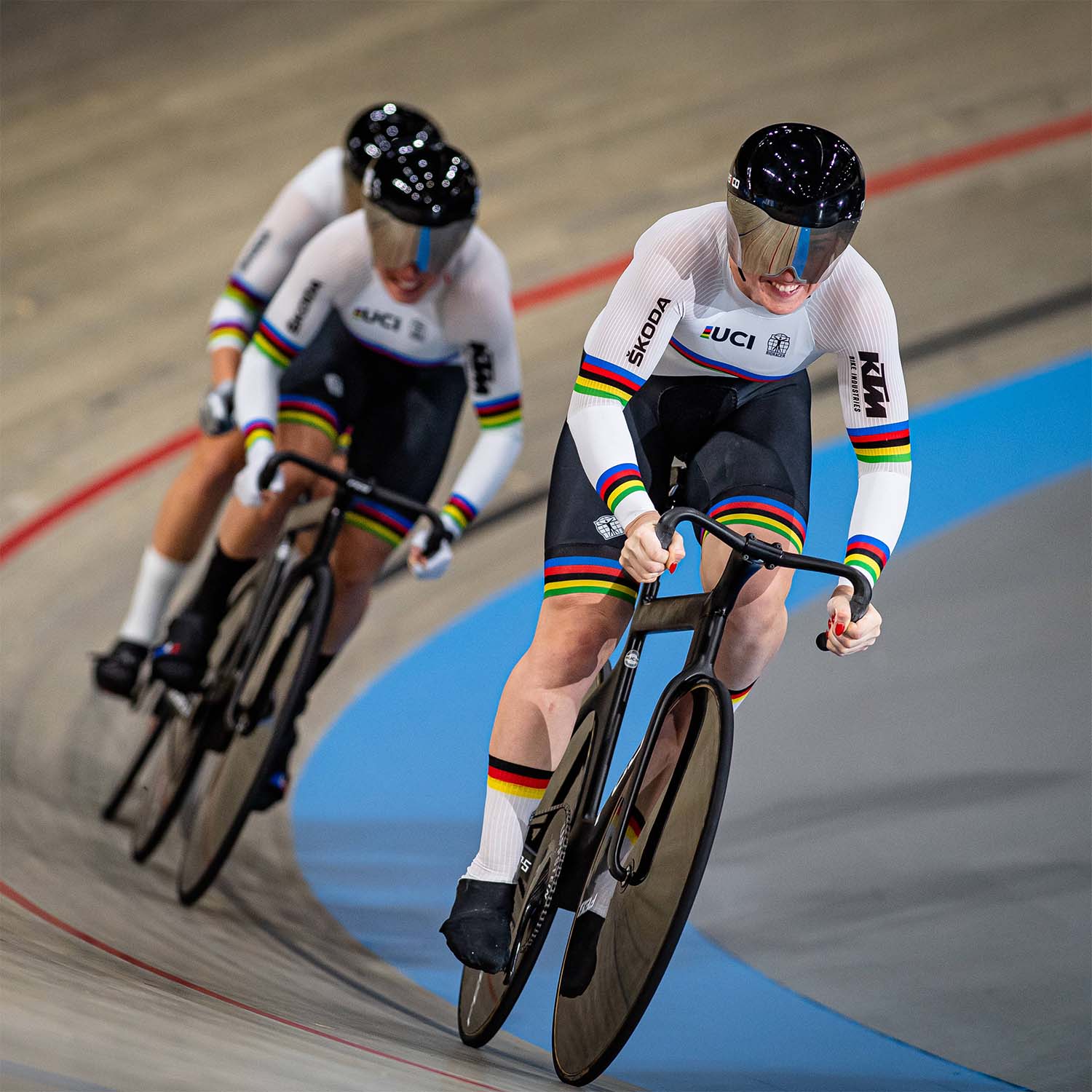 Team Germany's women cyclists in action during a track cycling race, wearing the official UCI rainbow kit by Bioracer, designed for maximum aerodynamics and performance.