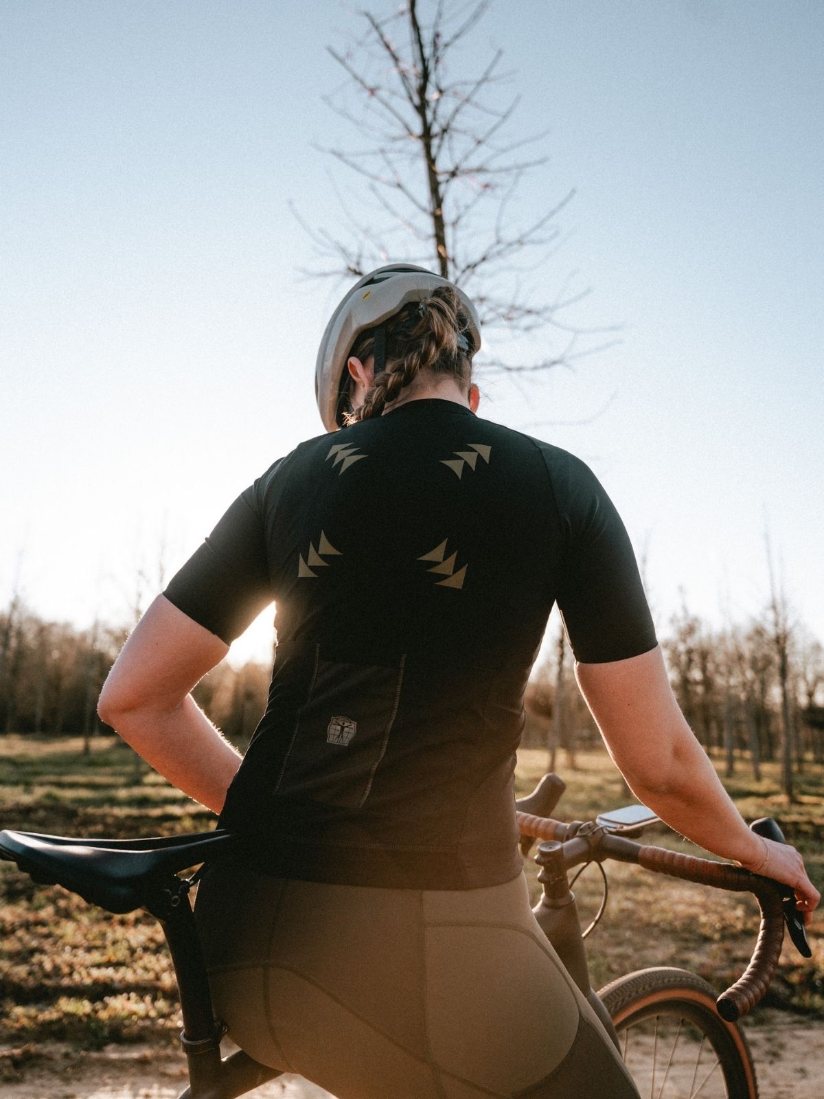 Female cyclist wearing Bioracer gravel jersey in Comfortable Body Fit cut during golden hour ride on forest trail