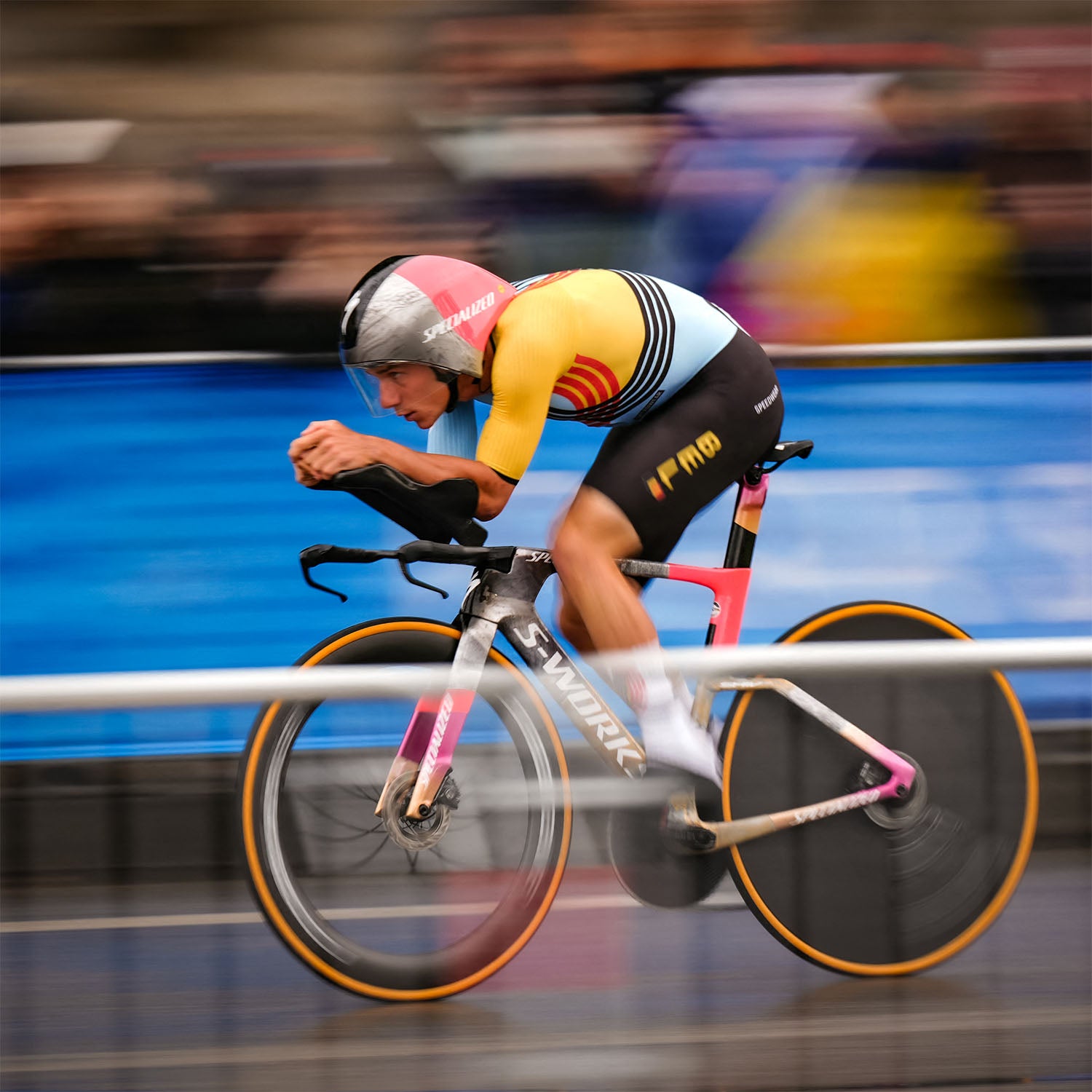 Remco Evenepoel in full time trial position wearing the Belgian national skinsuit and aero helmet, racing on a Specialized bike during a high-speed individual time trial.
