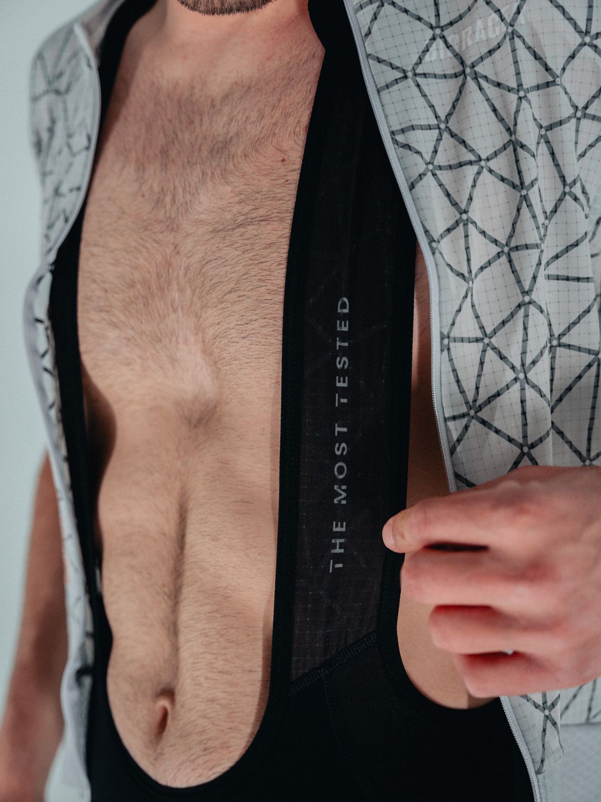Close-up of Bioracer Speedwear Graphene bibshort strap with “The Most Tested” print and lightweight mesh jersey opened