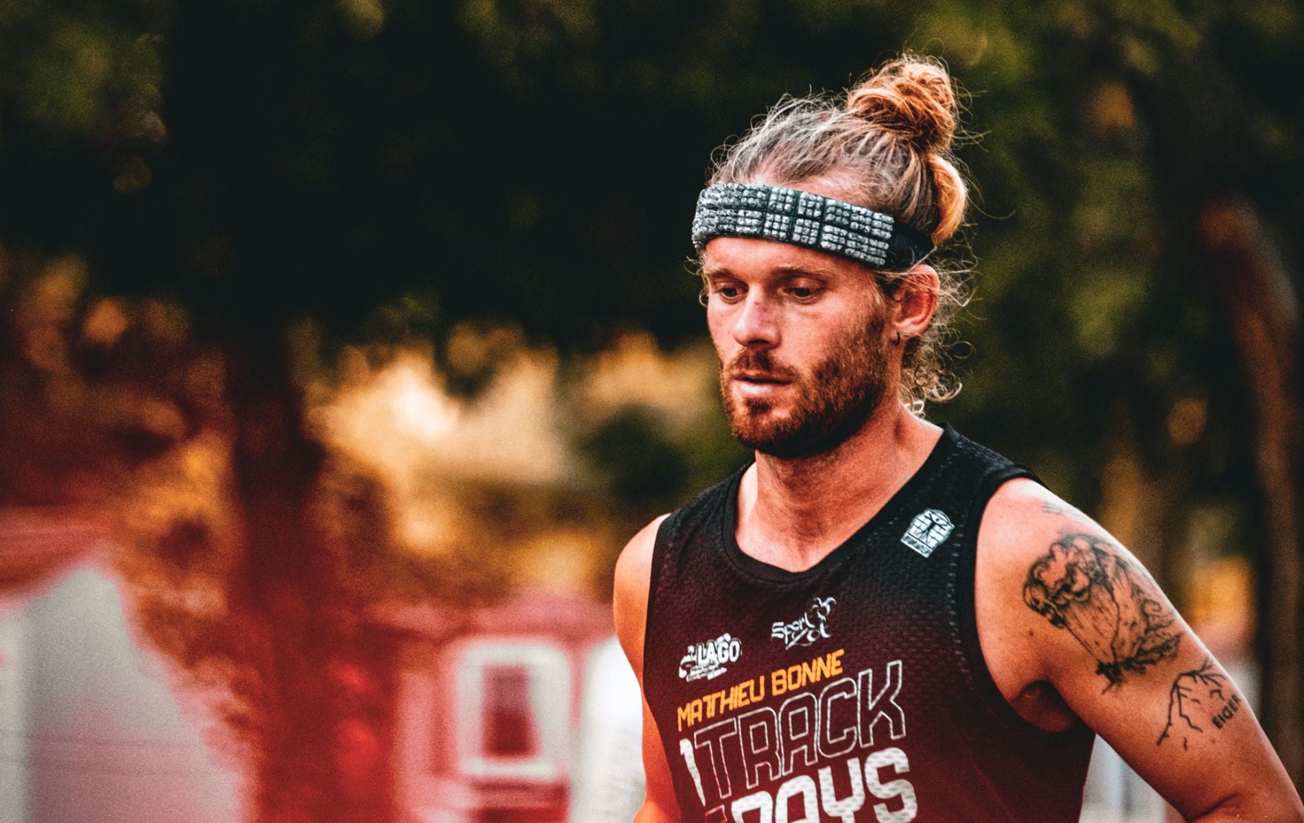 Close-up of ultra runner Matthieu Bonne in deep focus during his Track Days challenge, wearing a black race tank top and headband.