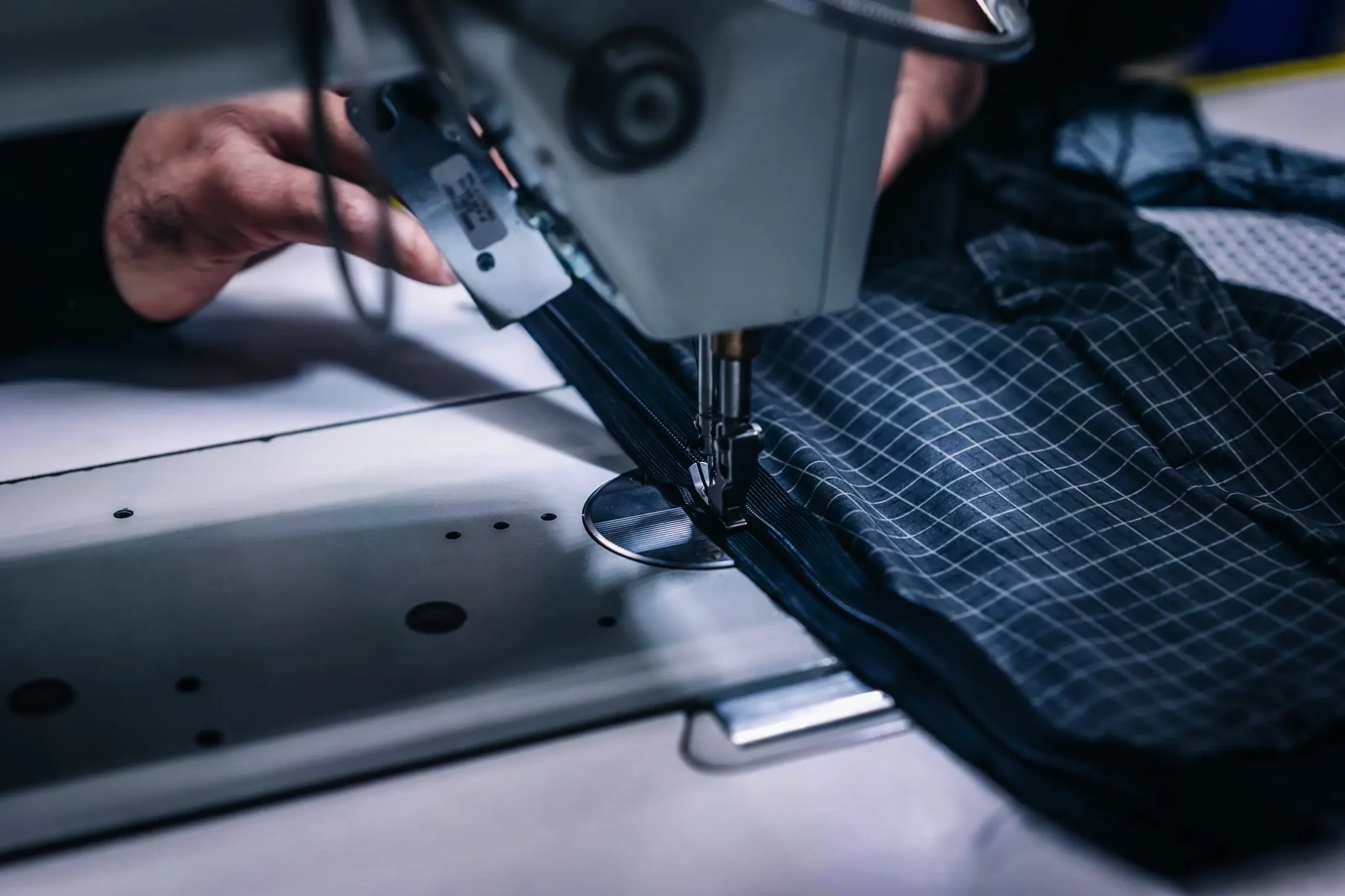 Close-up of professional stitching work on technical sportswear fabric in a textile studio, showing precision manufacturing and high-performance material.